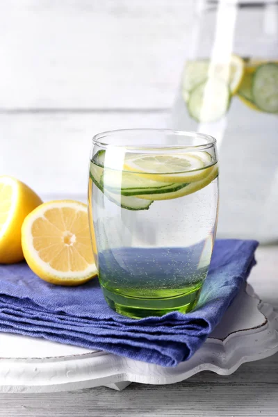 Свіжа вода з лимоном та огірком у скляному посуді на дерев'яному фоні — стокове фото
