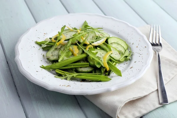 Ensalada verde con pepino, rúcula y cáscara de limón sobre fondo de madera —  Fotos de Stock