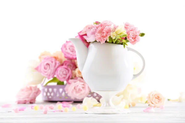 Composição com belas flores de primavera em bule de chá no fundo rosa claro — Fotografia de Stock