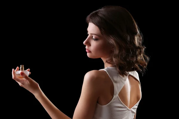 Beautiful woman with perfume bottle on black background — Stock Photo, Image