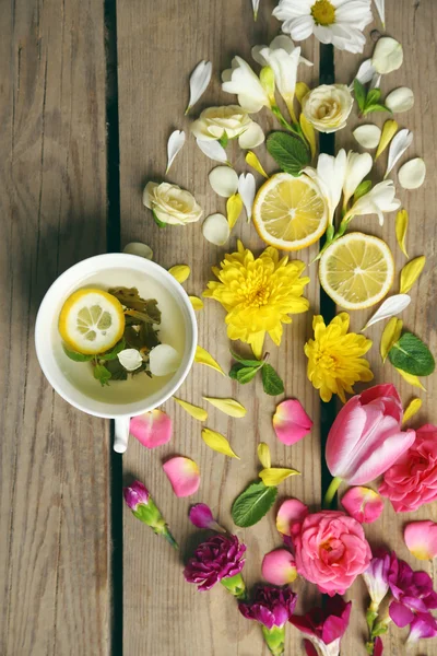 Xícara de chá de ervas com belas flores, em fundo de madeira — Fotografia de Stock