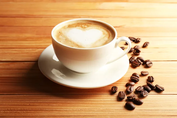 Cup of coffee latte art with grains on wooden background — Stock Photo, Image