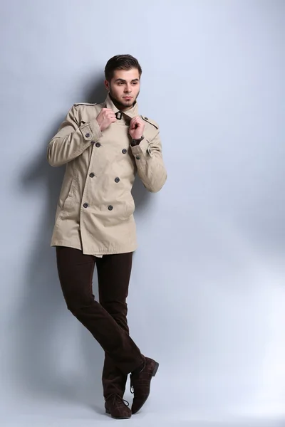 Young man in coat on gray background — Stock Photo, Image