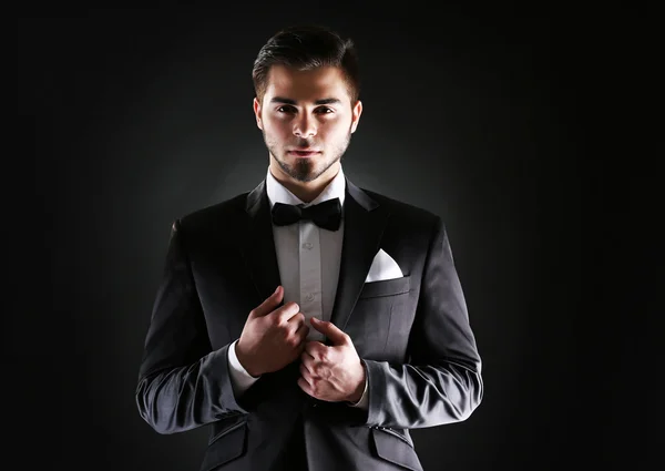 Uomo elegante in giacca e cravatta su sfondo scuro — Foto Stock