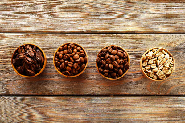 Coffee beans in small dishes on wooden background