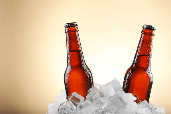 Garrafas de vidro de cerveja em cubos de gelo sobre fundo de cor — Fotografia de Stock