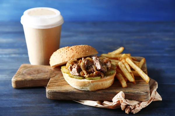 Hambúrguer saboroso e batatas fritas em fundo de mesa de madeira, close-up conceito de comida não saudável — Fotografia de Stock