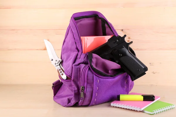 Gun in school backpack on wooden background — Stock Photo, Image