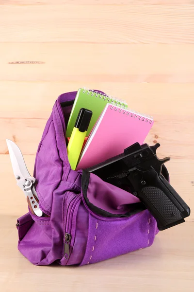 Gun in school backpack on wooden background — Stock Photo, Image