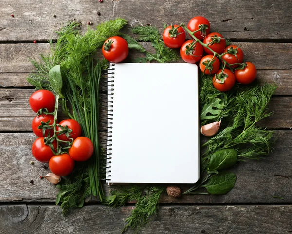 Livro de receitas aberto com ervas frescas, tomates e especiarias em fundo de madeira — Fotografia de Stock