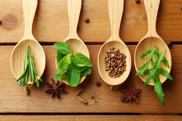 木制的勺子与新鲜的药草和香料木制背景 — 图库照片