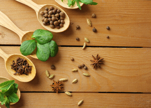 Wooden spoons with fresh herbs and spices on wooden background