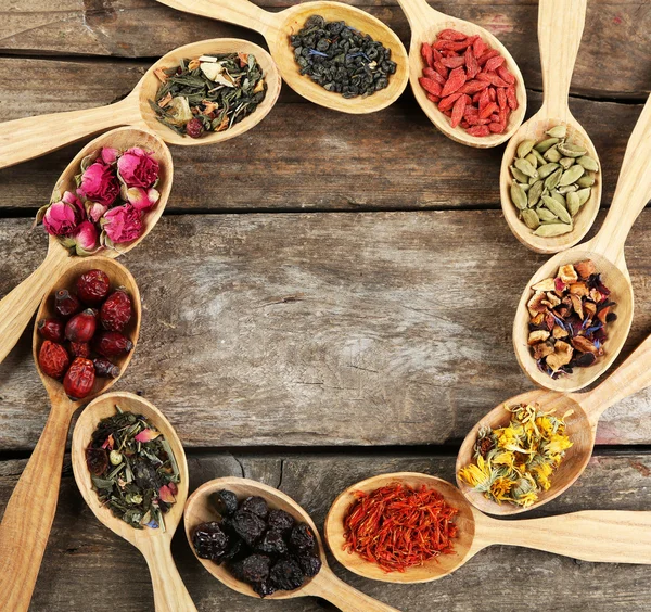 Collection of tea and natural additives in wooden spoons, on old wooden table — Stock Photo, Image