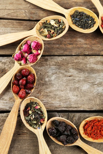 Collection of tea and natural additives in wooden spoons, on old wooden table — Stock Photo, Image