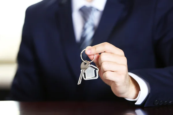 Geschäftsmann mit Schlüssel in der Hand im Büro vor verschwommenem Hintergrund — Stockfoto