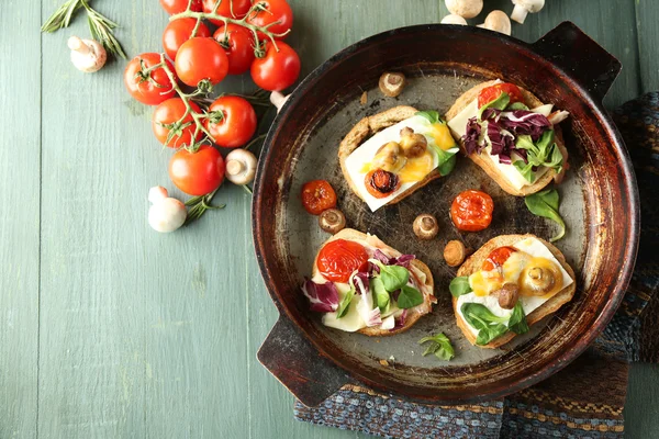 Tasty sandwiches on old pan, on wooden table — Stock Photo, Image