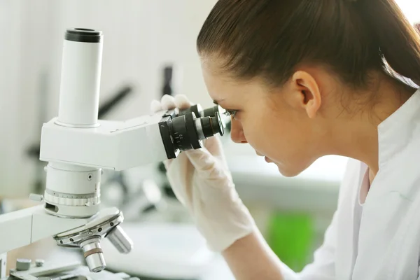 Científica mirando a través de un microscopio en laboratorio — Foto de Stock