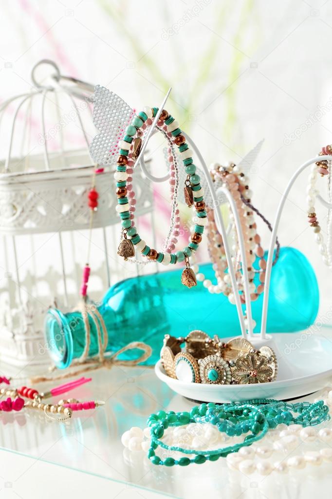 Decorative stand with jewelry and bijouterie on table in room