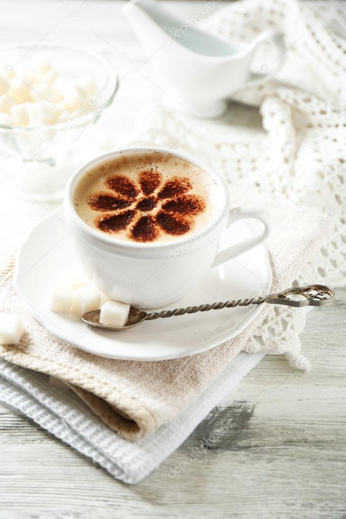 Cup of latte coffee art on wooden table, on light background