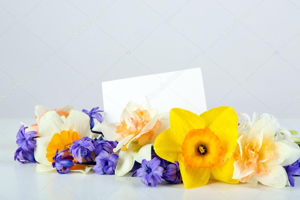 Beautiful bright flowers with card on light background