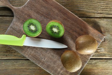 Kesme tahtası ahşap arka plan üzerinde bıçak ile sulu kivi