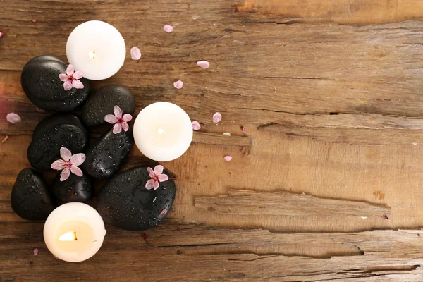 Spa stenen met kaarsen en Lentebloemen op tafel close-up — Stockfoto
