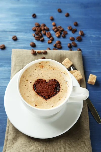 Cup of cappuccino with heart of cocoa on wooden table — Stock Photo, Image