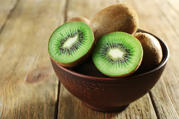 Juicy kiwi fruit in bowl on wooden background — Stock Photo, Image