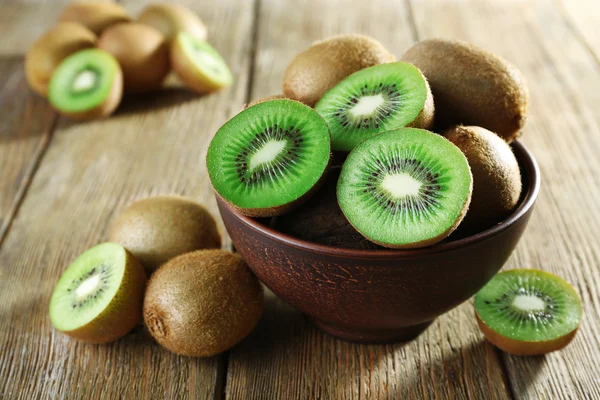 Sappige kiwi vruchten in kom op houten achtergrond — Stockfoto