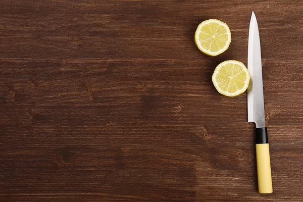 Halves of lemon with knife on wooden background — Stock Photo, Image