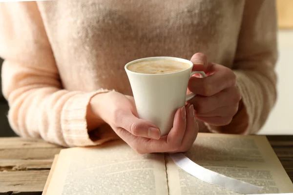 Женщина держит чашку кофе и читает книгу — стоковое фото