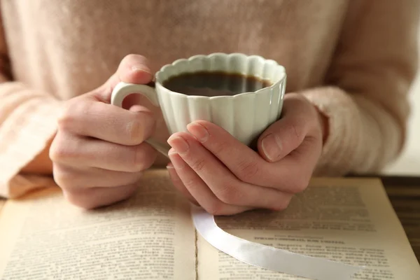 Mujer sosteniendo la taza de café y leer el libro — Foto de Stock