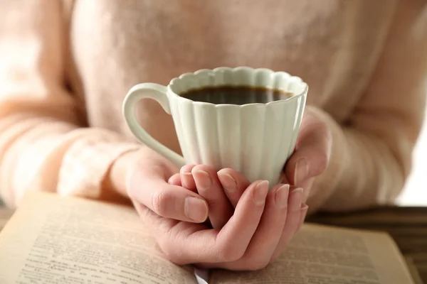 Mujer sosteniendo la taza de café y leer el libro —  Fotos de Stock