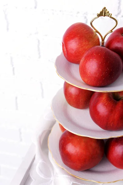 Sabrosas manzanas maduras en bandeja de servir sobre fondo de pared de ladrillo —  Fotos de Stock