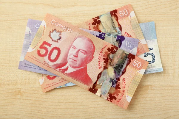 Kanadensiska dollar på träbord — Stockfoto