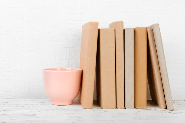 Knihy a pohár na dřevěné police — Stock fotografie