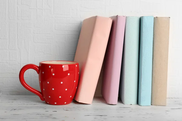 Books and cup on wooden shelf — Stock Photo, Image