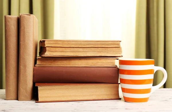 Boeken en cup op houten tafel — Stockfoto