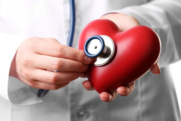 Médico mãos com estetoscópio e coração vermelho — Fotografia de Stock