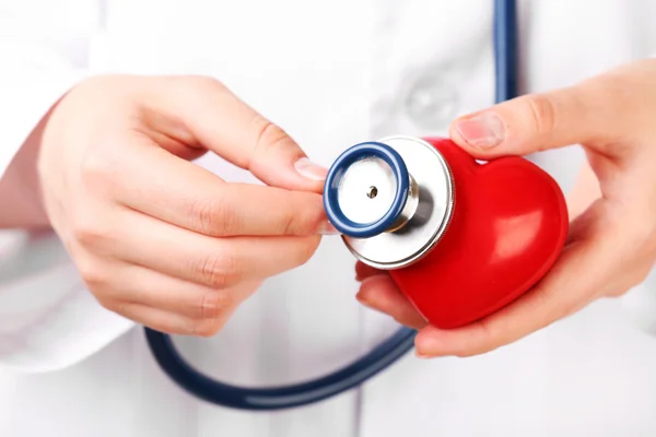 Läkare händerna med stetoskop och rött hjärta — Stockfoto