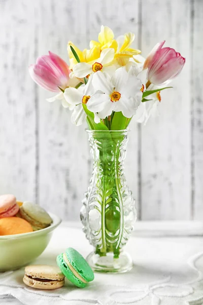 Bahar buket vazo ve renk ahşap arka plan üzerinde lezzetli macaroons — Stok fotoğraf