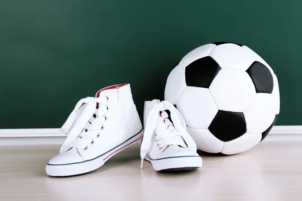 Scarpe sportive e pallone da calcio su sfondo lavagna — Foto Stock