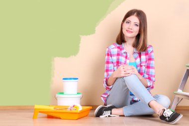 Güzel kız boyama duvar için ekipman ile yerde yatarken