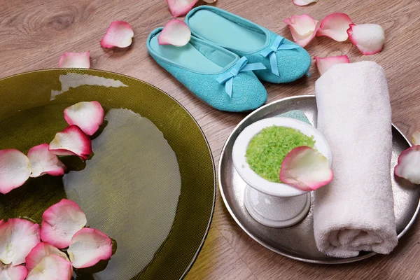 Spa bowl with water, rose petals, towel and slippers on light background. Concept of pedicure or natural spa treatment — Stock Photo, Image