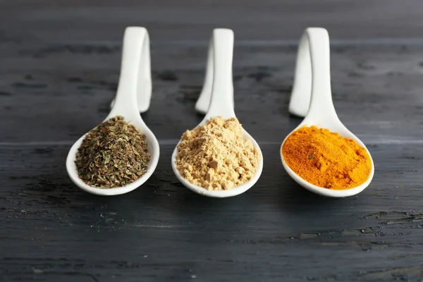 Different kinds of spices in spoons on wooden background — Stock Photo, Image