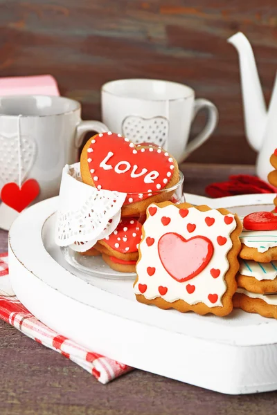Soubory cookie pro valentinky den, konvice a šálky na barevné dřevěné pozadí ve tvaru srdce — Stock fotografie