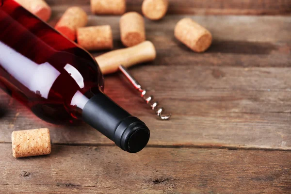 Bouteille de vin en verre avec bouchons et tire-bouchon sur fond de table en bois — Photo