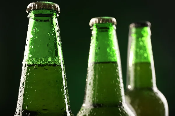 Botellas de vidrio de cerveza sobre fondo verde oscuro — Foto de Stock