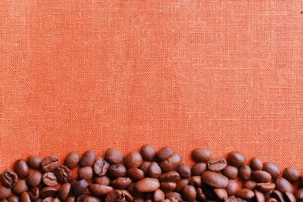 Кадр кофейных зерен на цветном фоне мешковины — стоковое фото