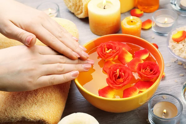 Female hands with bowl of aroma spa water on wooden table, closeup — Stock Photo, Image